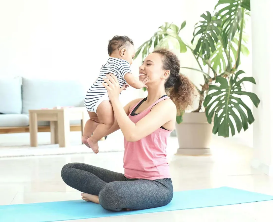 Une jeune maman souriante avec son bébé lors d'une séance de gym postnatale